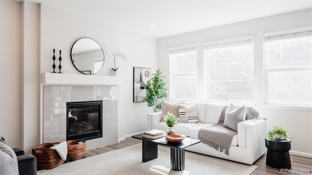 living room with a glass covered fireplace, recessed lighting, baseboards, and wood finished floors