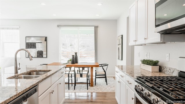 17850 W 94th Dr, Arvada, CO 80007 - kitchen with stainless steel appliances, a sink, light wood-style floors, white cabinetry, and recessed lighting