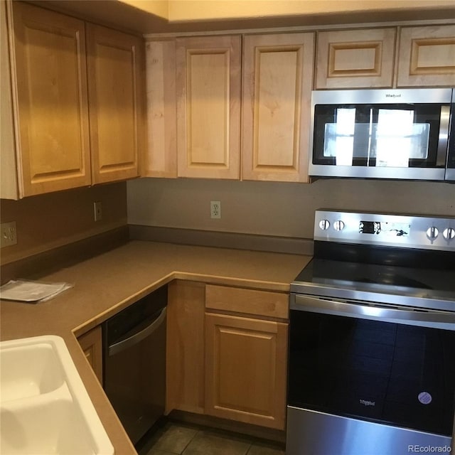 kitchen with light brown cabinets, a sink, appliances with stainless steel finishes, light countertops, and tile patterned flooring