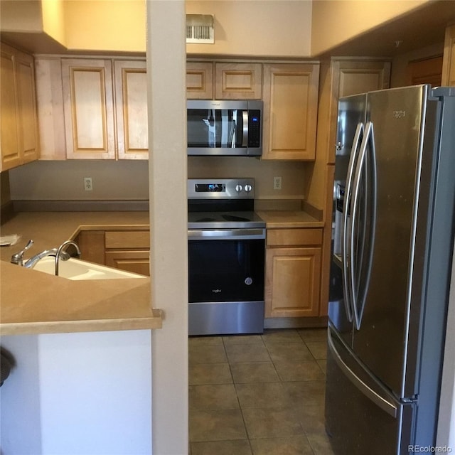 kitchen featuring a sink, stainless steel appliances, dark tile patterned floors, and light countertops