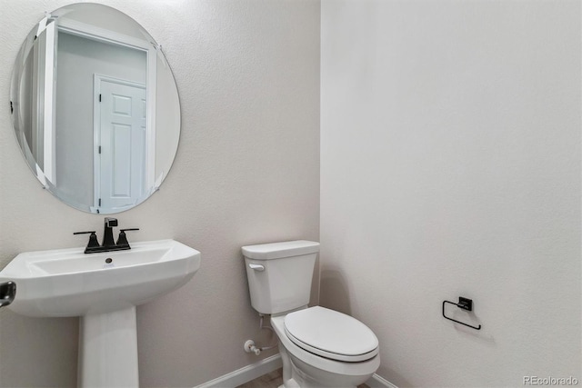 bathroom featuring a sink, toilet, and baseboards