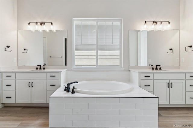 full bath with a garden tub, a sink, and wood finished floors