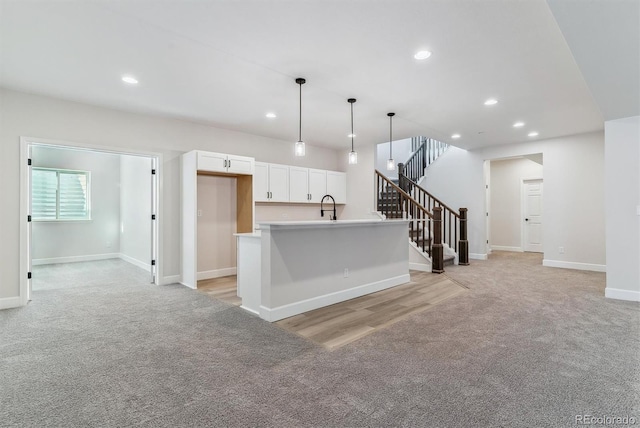 kitchen featuring recessed lighting, a sink, white cabinetry, and light colored carpet