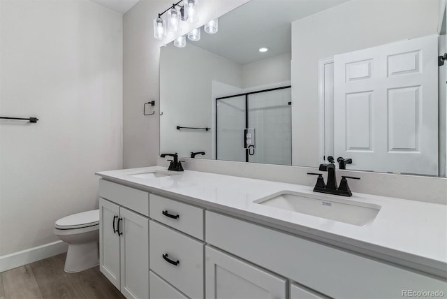 full bathroom with wood finished floors, a stall shower, a sink, and toilet