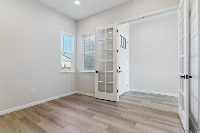 spare room featuring light wood-style floors, baseboards, and french doors