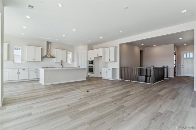 unfurnished living room with light wood-style floors, recessed lighting, visible vents, and a sink