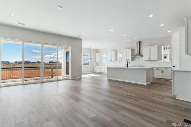 unfurnished living room featuring recessed lighting, a sink, wood finished floors, baseboards, and visible vents