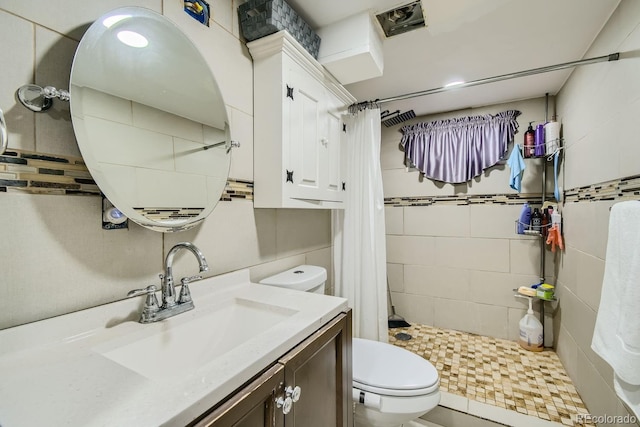 bathroom featuring vanity, toilet, walk in shower, and tile walls