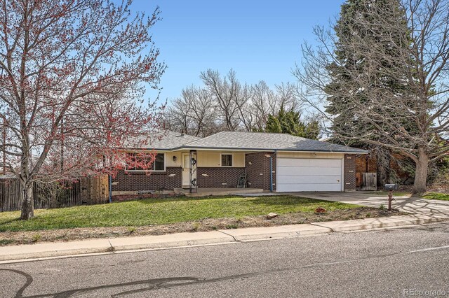 ranch-style house featuring concrete driveway, fence, a front lawn, brick siding, and a garage