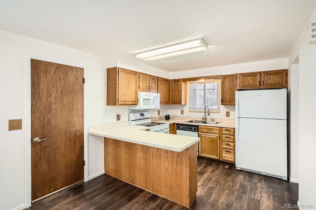kitchen with light countertops, white appliances, dark wood-style flooring, a sink, and a peninsula