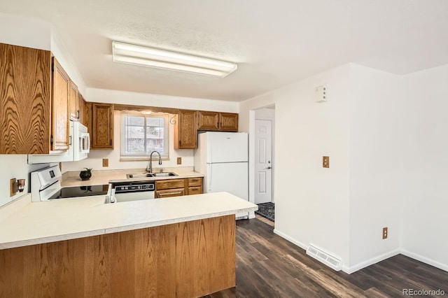 kitchen with light countertops, white appliances, a sink, visible vents, and brown cabinets