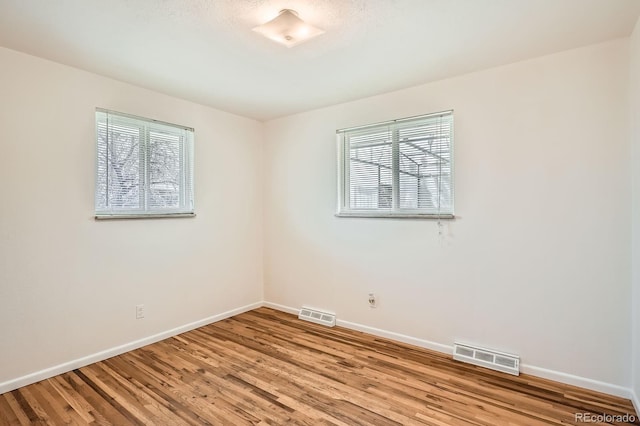 unfurnished room featuring baseboards, visible vents, and light wood-type flooring