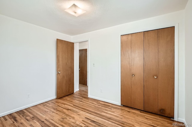 unfurnished bedroom with baseboards, a closet, and wood finished floors