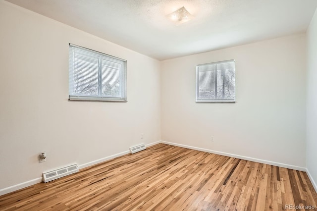 empty room featuring baseboards, visible vents, and wood finished floors