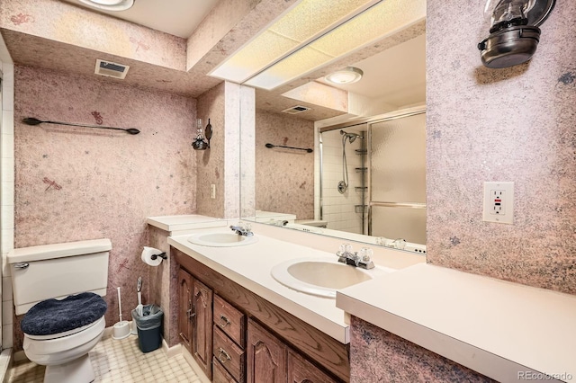 bathroom featuring visible vents, a sink, toilet, and a stall shower