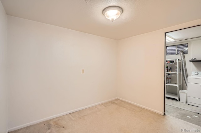 spare room with light carpet, baseboards, washer / clothes dryer, and a textured ceiling