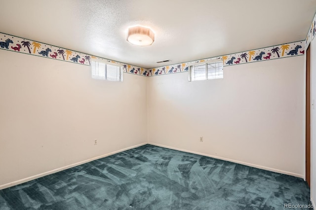 empty room featuring a textured ceiling, visible vents, a healthy amount of sunlight, and dark colored carpet