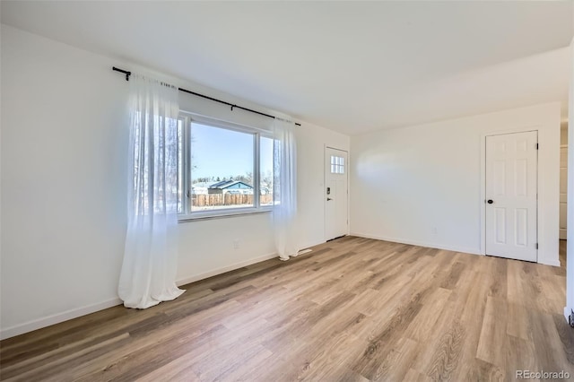 empty room featuring baseboards and light wood-style floors