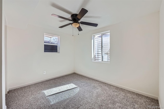 carpeted empty room with plenty of natural light, a ceiling fan, and baseboards