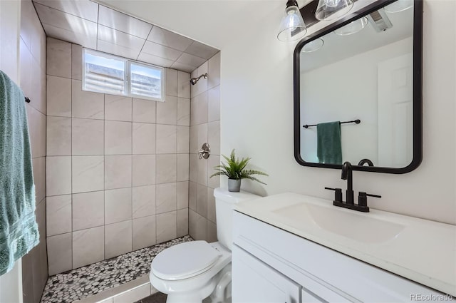 full bathroom with toilet, tiled shower, and vanity