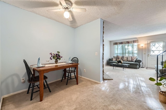 dining area featuring a textured ceiling, plenty of natural light, baseboards, a ceiling fan, and carpet floors