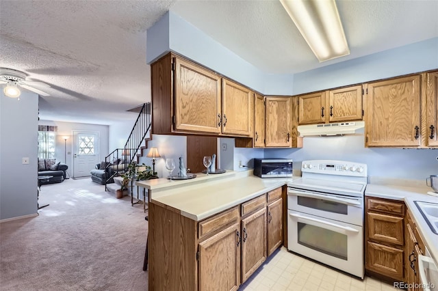 kitchen featuring double oven range, under cabinet range hood, open floor plan, light countertops, and a textured ceiling