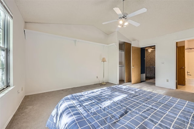 unfurnished bedroom with carpet flooring, multiple windows, vaulted ceiling, ensuite bath, and a closet