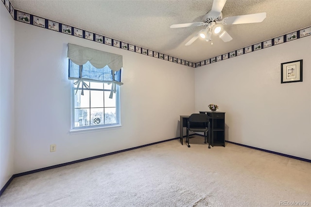 carpeted spare room featuring a textured ceiling, baseboards, ceiling fan, and a desk