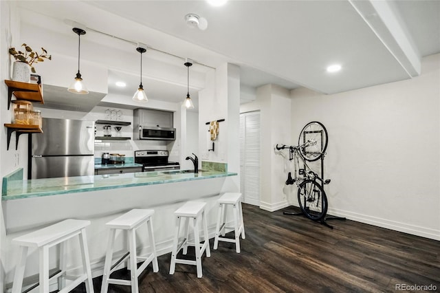 kitchen featuring a breakfast bar area, stainless steel appliances, pendant lighting, dark hardwood / wood-style flooring, and kitchen peninsula