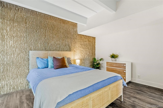 bedroom with beamed ceiling, dark wood-type flooring, and baseboards