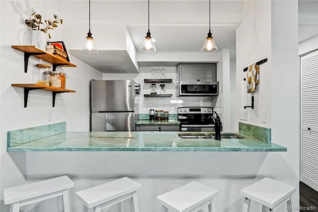 kitchen with backsplash, open shelves, appliances with stainless steel finishes, a peninsula, and a sink