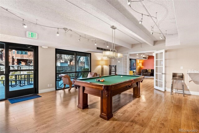 playroom with baseboards, light wood finished floors, pool table, french doors, and a textured ceiling