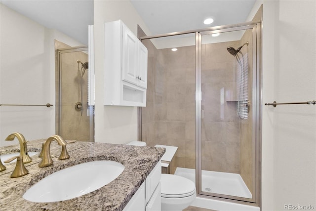 bathroom featuring vanity, toilet, and a shower with door