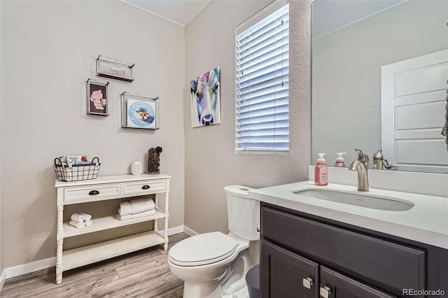 bathroom featuring vanity, hardwood / wood-style flooring, a wealth of natural light, and toilet