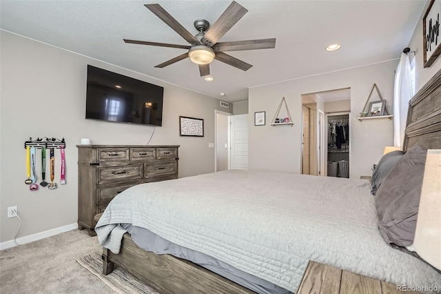 carpeted bedroom featuring ceiling fan, a closet, and a walk in closet