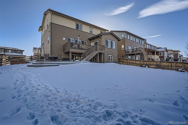 snow covered house featuring a wooden deck