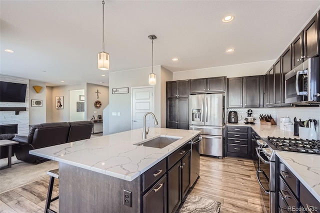 kitchen with sink, dark brown cabinets, pendant lighting, and appliances with stainless steel finishes