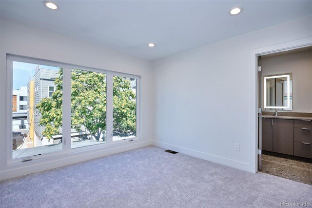 empty room featuring recessed lighting, a sink, visible vents, and carpet floors