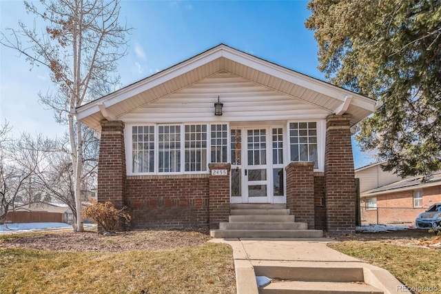 bungalow-style house featuring entry steps, brick siding, and a front lawn