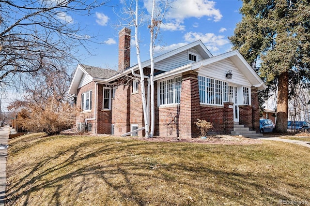 view of home's exterior with entry steps, a chimney, a lawn, and brick siding