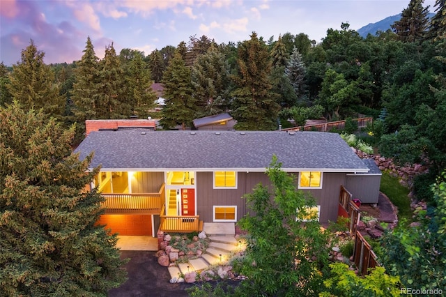 2434 Virgo Dr, Colorado Springs, CO 80906 - view of front of house featuring a shingled roof, a garage, driveway, and a forest view