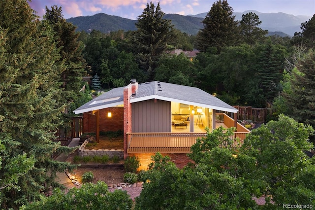 2434 Virgo Dr, Colorado Springs, CO 80906 - view of front facade featuring a chimney, a wooded view, and a deck with mountain view