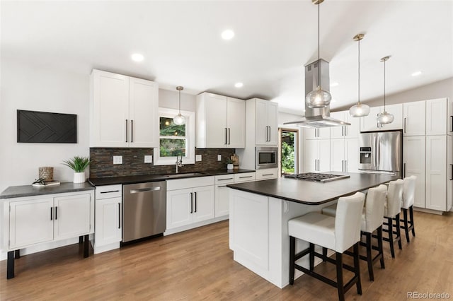 2434 Virgo Dr, Colorado Springs, CO 80906 - kitchen with stainless steel appliances, island range hood, dark countertops, backsplash, and white cabinetry