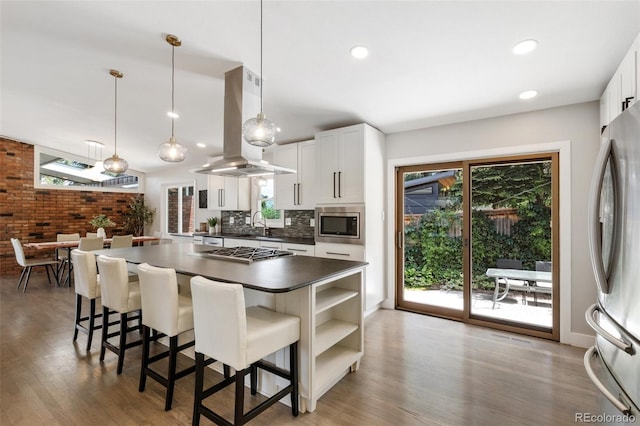 2434 Virgo Dr, Colorado Springs, CO 80906 - kitchen with island range hood, stainless steel appliances, dark countertops, wood finished floors, and recessed lighting