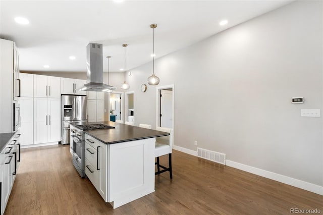 2434 Virgo Dr, Colorado Springs, CO 80906 - kitchen featuring island range hood, dark countertops, stainless steel appliances, a breakfast bar, and white cabinetry