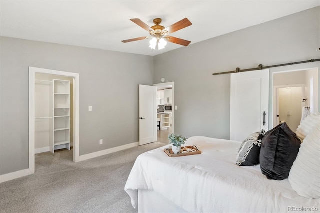 2434 Virgo Dr, Colorado Springs, CO 80906 - bedroom featuring a barn door, a spacious closet, light colored carpet, a ceiling fan, and a closet