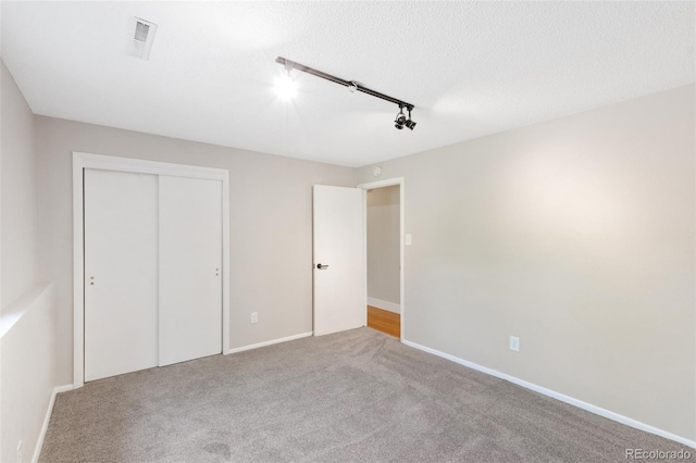 2434 Virgo Dr, Colorado Springs, CO 80906 - unfurnished bedroom featuring rail lighting, carpet floors, and a closet