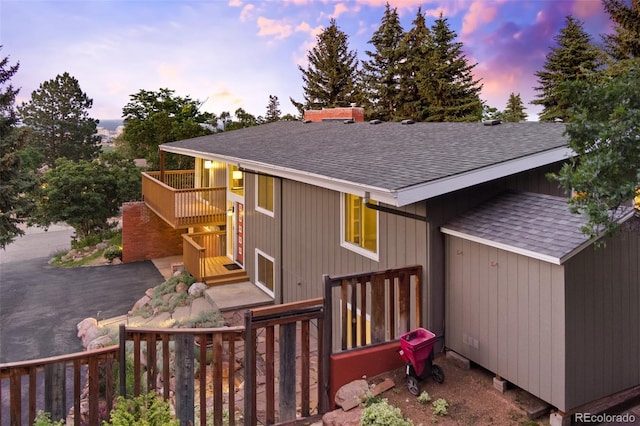 2434 Virgo Dr, Colorado Springs, CO 80906 - back of property at dusk featuring a shingled roof, a wooden deck, a chimney, and stairway