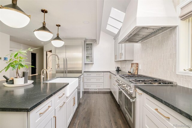 40 S Dexter St, Denver, CO 80246 - kitchen with custom exhaust hood, range with two ovens, dark wood-style floors, decorative backsplash, and glass insert cabinets