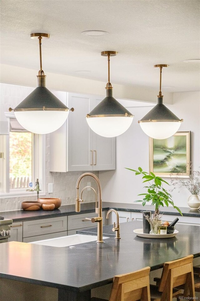 40 S Dexter St, Denver, CO 80246 - kitchen featuring dark countertops, hanging light fixtures, decorative backsplash, and a breakfast bar